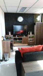 a living room with a couch and a tv at Acosta Ñu Apart Hotel in Asunción