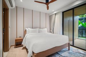 a bedroom with a white bed and a large window at Laguna Beachside Residences Building 2 by Banyan Living in Bang Tao Beach