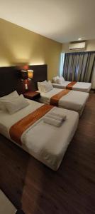 a row of four beds in a hotel room at GR Ming garden SCSP in Kota Kinabalu