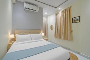 a bedroom with a white bed and a window at Hotel Broholi Height Inn Near Hafeezpet Railway Station in Hyderabad