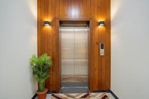 a hallway with a elevator with a plant in it at Hotel Broholi Height Inn Near Hafeezpet Railway Station in Hyderabad
