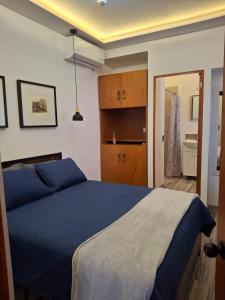 a bedroom with a blue bed and a bathroom at Noa Loft in Miravalle