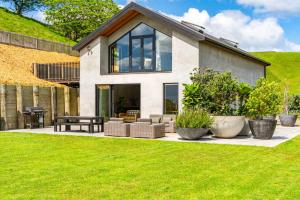 ein Haus mit großen Fenstern und einem grünen Rasen in der Unterkunft Private Beach Access - Mangawhai in Mangawhai