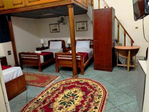 a bedroom with two beds and a table and a rug at City House Guesthouse in Cairo