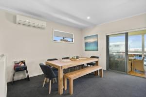 a dining room with a wooden table and chairs at Bayview Escape - Aldinga Beach - C21 SouthCoast Holidays in Aldinga Beach