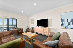 a living room with couches and a flat screen tv at Bayview Escape - Aldinga Beach - C21 SouthCoast Holidays in Aldinga Beach
