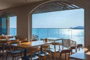 een restaurant met tafels en stoelen en een groot raam bij Qingdao Momer Cliff Ocean View Villas in Qingdao +6 foto's