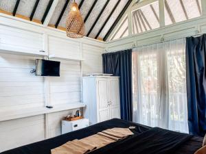 une chambre avec un lit, une télévision et une fenêtre dans l'établissement Bingin Sun & Moon Villas, à Bingin Beach 39 autres photos