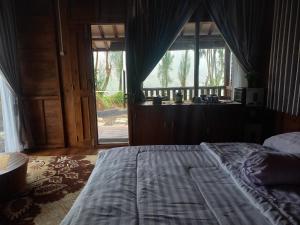 ein Schlafzimmer mit einem Bett und einem großen Fenster in der Unterkunft Jati mulyo Cottage Dieng in Batur