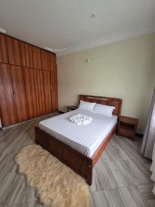 a bedroom with a bed with white sheets and a rug at Express living and wellness in Jinja
