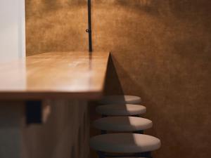 a row of stools sitting next to a table at Shijo Guesthouse HIVE in Kyoto +36 photos