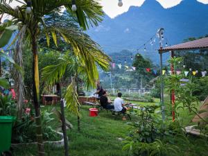 dos personas sentadas en un banco en un jardín en Đồi Gió Homestay & Campsite, en Ha Giang