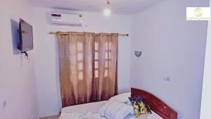 a room with a curtain and a couch and a television at Résidence Suzanne in Brazzaville