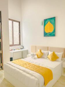 a white bedroom with a large bed with yellow pillows at Trident Kandy in Kandy