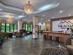 een lobby met een wachtruimte met stoelen en een projectiescherm bij Wilacha Chiang Rai in Chiang Rai
