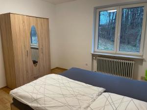 a bedroom with a bed and a cabinet and two windows at Ferienhaus Heiligenmühle in Leinburg