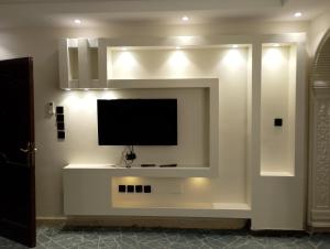 a living room with a tv on a wall at Al Madinah Hotel in Al Madinah