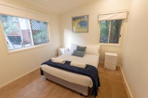 een kleine slaapkamer met een bed en twee ramen bij Sandcastles 2 in Point Lookout