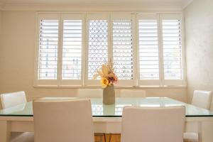 a dining room with a glass table and white chairs at Seaside Apartments Broadbeach in Gold Coast