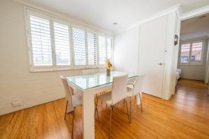 a dining room with a glass table and white chairs at Seaside Apartments Broadbeach in Gold Coast