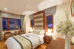 a hotel room with a bed and a vase of flowers at Moonlight Hotel & Apartment in Da Nang