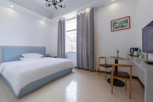 a white bedroom with a bed and a desk and a table at Hua Han Hotel in Zhangjiajie