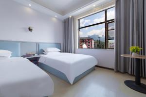 a hotel room with two beds and a window at Hua Han Hotel in Zhangjiajie