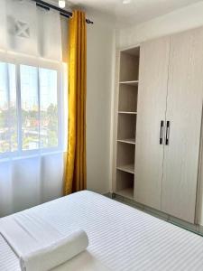 a bedroom with a white bed and a window at BUXTON New Furnished Apartments in Mombasa +15 photos