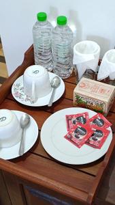 a wooden table with plates and spoons and water bottles at Ameliora Hotel Ella in Ella