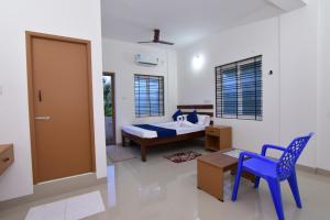 ein Zimmer mit einem Bett, einem Tisch und einem Stuhl in der Unterkunft Pondicherry Comfort Rooms in Puducherry + 23 Fotos