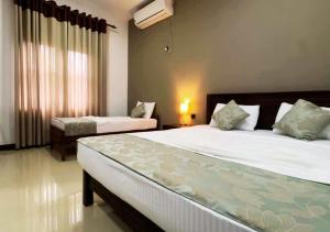 a bedroom with two beds and a window at Osara Holiday Home in Anuradhapura