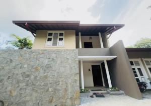 a house with a stone wall in front of it at Osara Holiday Home in Anuradhapura