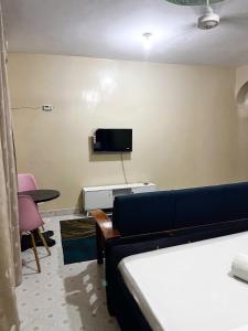 a bedroom with a couch and a tv on the wall at Mombasa Town CBD Studio in Mombasa