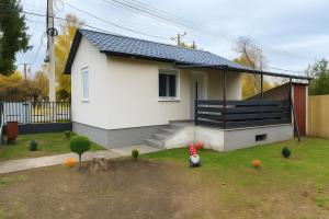 a small white house with a black roof at Rigókert Vendégház in Lakitelek +16 photos