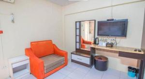 ein orangefarbener Stuhl in einem Zimmer mit Schreibtisch und Fernseher in der Unterkunft Nornnan Hotel in Nan