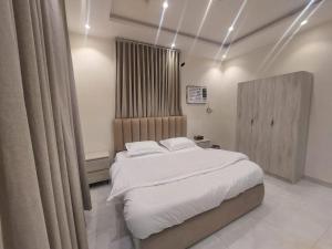 a bedroom with a large bed with white sheets at شقة غرفتين وصالة in Jeddah