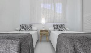 a white room with two beds and a night stand at Villa de Luxe in San José