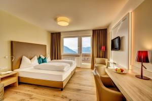 a hotel room with a large bed and a desk at Garni Hotel Kessler in Tirolo