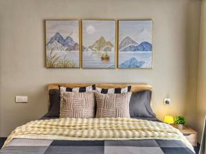 a bedroom with a bed with four paintings on the wall at R&F Princess Cove 3BR, Sea View, JB CIQ, by Good Life Homestay in Johor Bahru