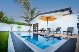 a swimming pool with an umbrella next to a house at Villa D8 in Mirissa