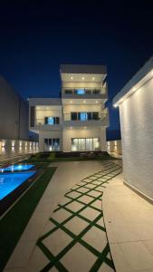 a large building with a swimming pool at night at شالية ماربيا الاشخرة Marbella Ashkhara Chalet in Al Ashkharah +10 photos