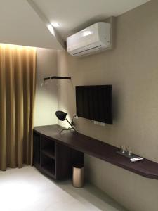 a room with a television and a desk with a lamp at Kenting Feliz Hotel in Kenting