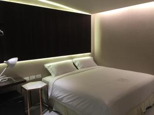 a bedroom with a white bed and a desk with a lamp at Kenting Feliz Hotel in Kenting