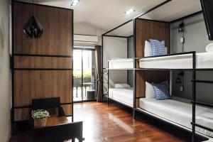 a room with three bunk beds and a room with a table at Journey Hostel Surat in Ban Tha Kup