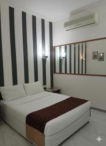 1 dormitorio con 1 cama con rayas blancas y negras en Makran Palace Hotel, en Ma‘ābīlah