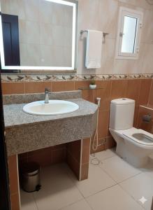 Un baño con lavabo, inodoro y espejo. en Makran Palace Hotel, en Ma‘ābīlah