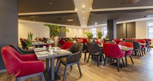 a dining room with tables and red chairs at PLAZA INN Grevenbroich in Grevenbroich