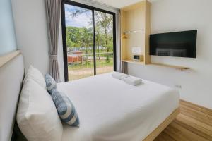 Un dormitorio con una cama blanca con una ventana grande. en Sea Side at Ao Nang Landmark Night Market Krabi, en Ban Khlong Haeng