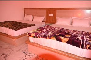two beds sitting next to each other in a room at Malwa resort in Chitrakoot +3 photos