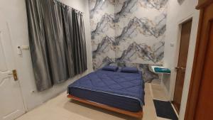 een klein bed in een kamer met een muur bij Gedung Putih Syariah in Palas 2